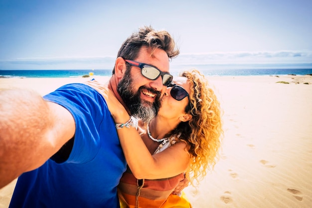 Una pareja adulta de turistas se toman una foto selfie en la playa con arena y océano azul y cielo de fondo Un hombre y una mujer felices disfrutando juntos de las vacaciones de verano Gente de estilo de vida de viaje