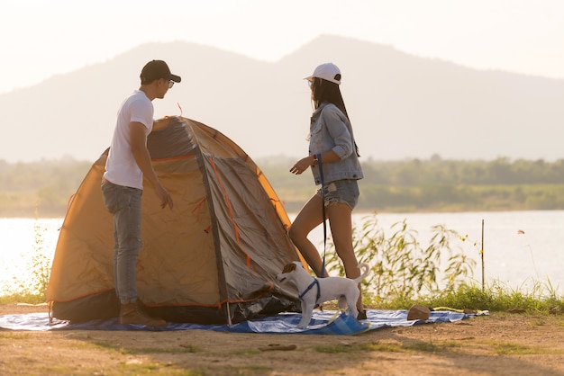 Foto pareja de adultos jóvenes asiáticos echan una carpa para acampar alrededor del lago.