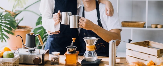 Una pareja de adultos jóvenes felices haciendo el desayuno y bebiendo café juntos en la acogedora cocina de casa por la mañana en casa preparando comidas y sonriendo estilo de vida ocio y concepto de amor