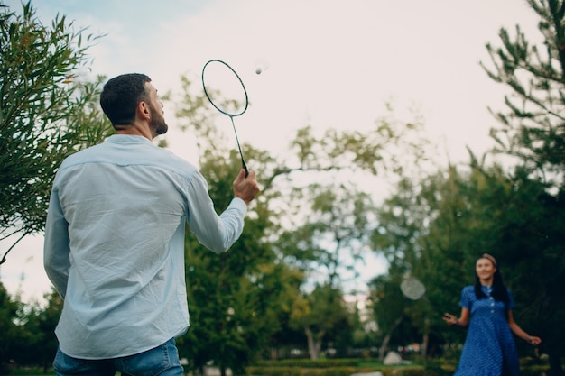 Pareja de adultos jóvenes jugando al bádminton en el parque.