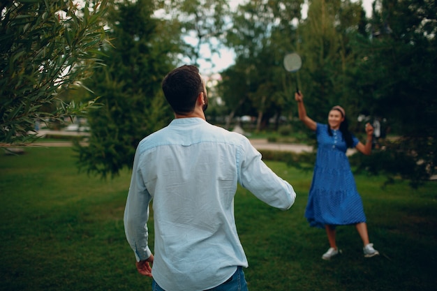 Pareja de adultos jóvenes jugando al bádminton en el parque.