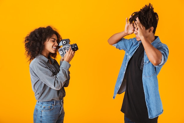 Pareja africana joven alegre que se encuentran aisladas, haciendo un video con cámara