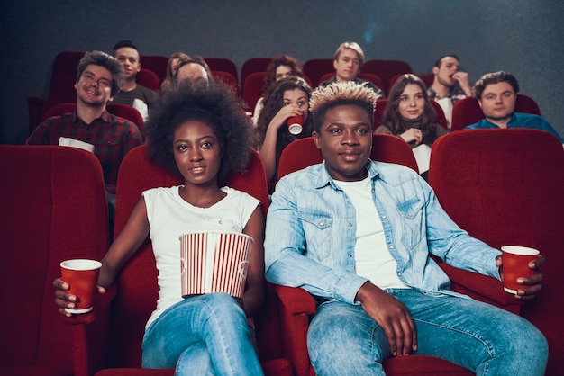 Pareja africana con palomitas viendo películas en el cine.