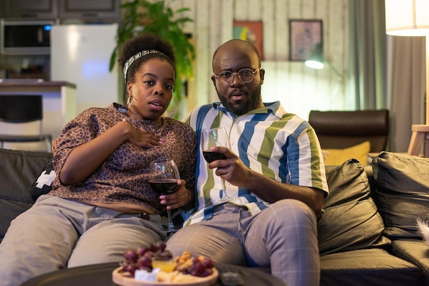 Pareja africana viendo una película de miedo en casa