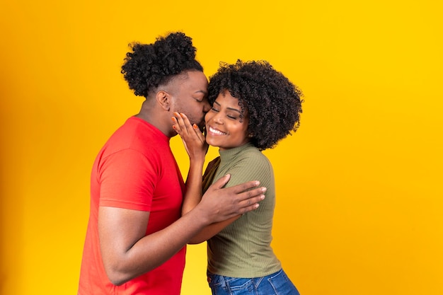 Pareja afro enamorada intercambiando abrazos y afecto sobre fondo amarillo