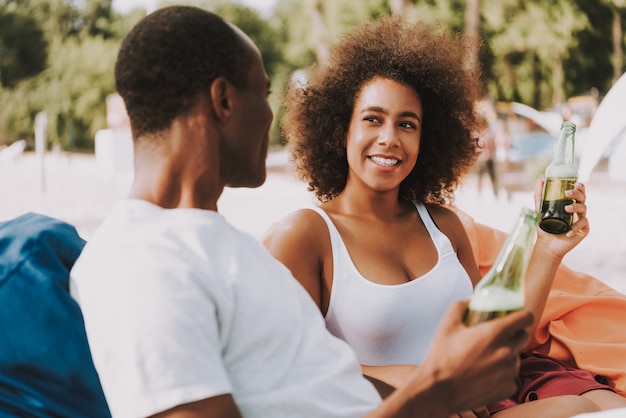 Pareja afroamericana bebe cerveza en la playa