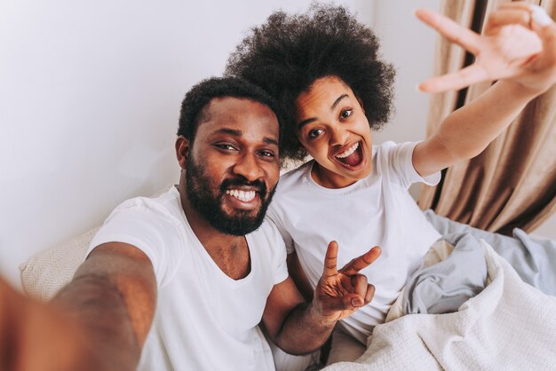 Pareja afroamericana en la cama Real hermosa y alegre pareja de amantes en casa