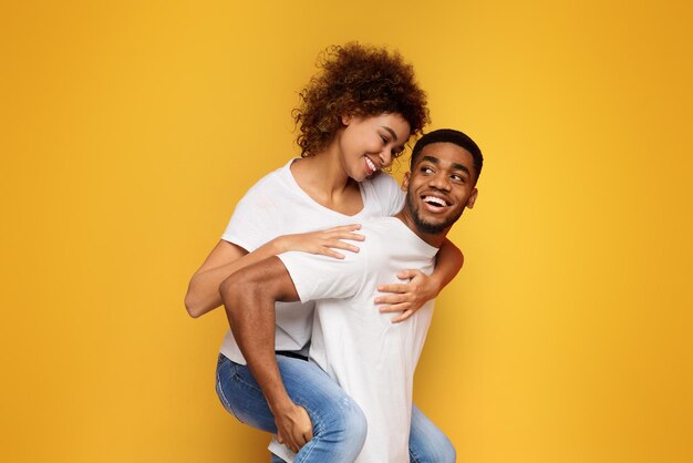 Una pareja afroamericana divirtiéndose en un fondo naranja.