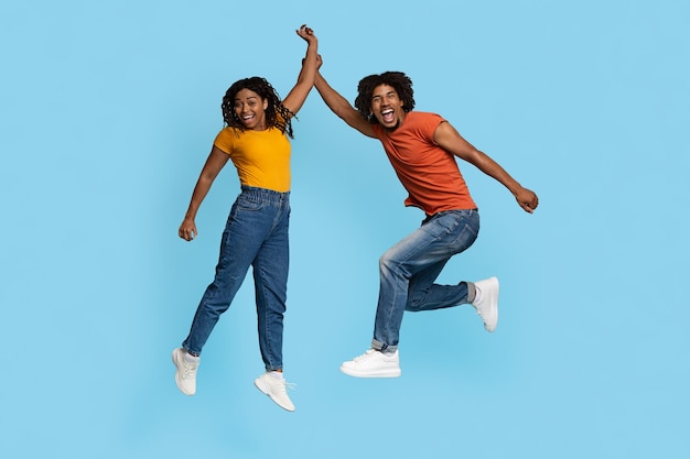 Pareja afroamericana emocional celebrando el éxito en azul