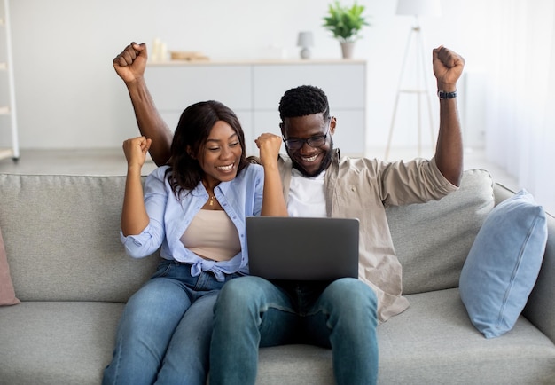 Pareja afroamericana sentada en el sofá usando pc