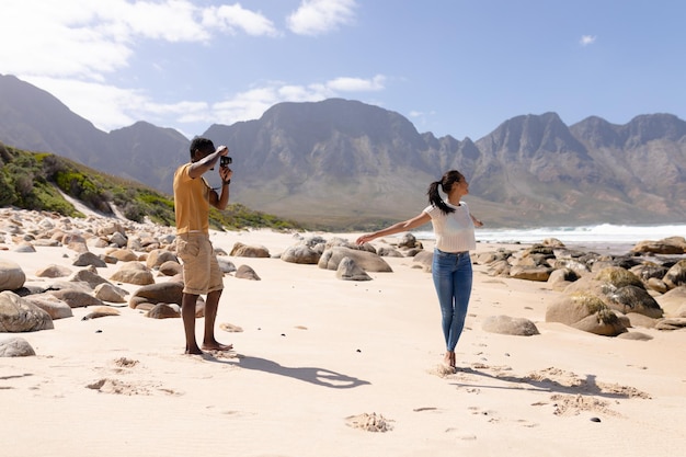 Pareja afroamericana tomando fotos en una playa junto al mar. estilo de vida saludable, ocio en la naturaleza.