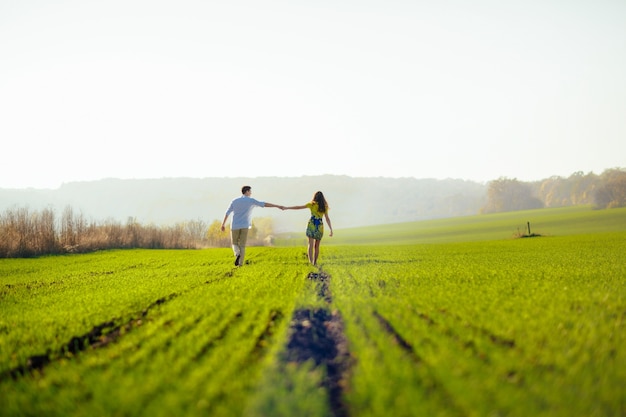 Pareja agarrada de la mano en un cultivo verde