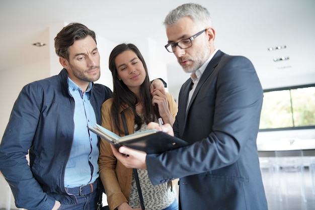 Pareja con agente inmobiliario visitando casa moderna