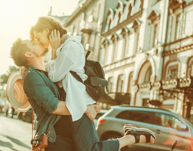 Pareja alegre alegre hipster enamorados besándose en la ciudad
