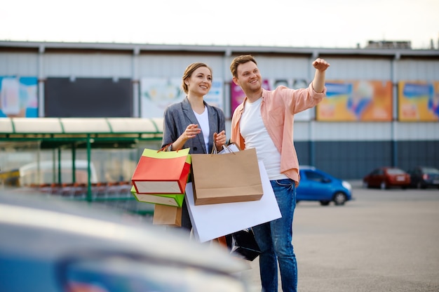 Foto pareja alegre con bolsas en el estacionamiento del supermercado