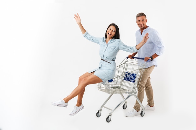 Pareja alegre caminando con un carrito de compras