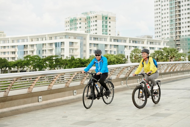 Pareja alegre ciclismo en puente