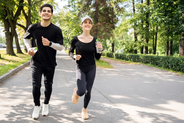 Una pareja alegre corriendo juntos en un parque exuberante promoviendo la salud y el fitness con un brillo y