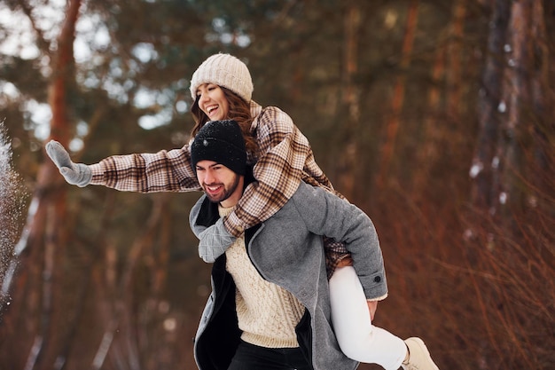 Una pareja alegre da un paseo por el bosque de invierno durante el día