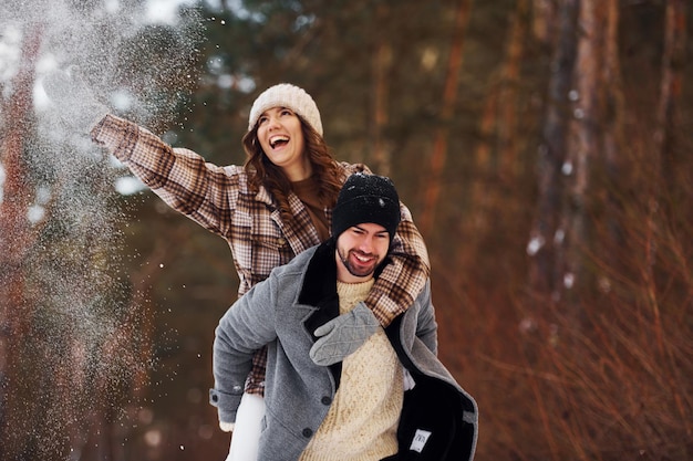 Una pareja alegre da un paseo por el bosque de invierno durante el día