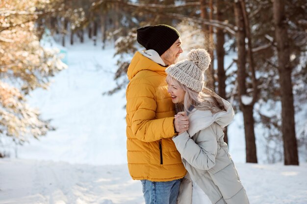 Pareja alegre se divierte riendo y sonriendo en el bosque al aire libre en invierno