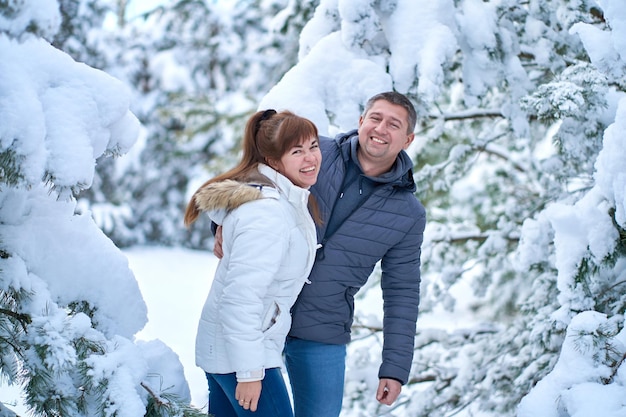 Una pareja alegre enamorada caminando en un bosque invernal cubierto de nieve