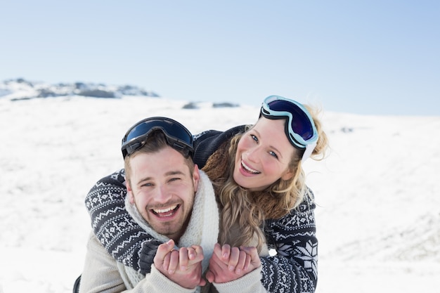 Pareja alegre con gafas de esquí en la nieve