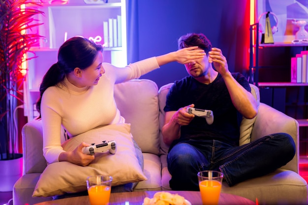 Una pareja alegre jugando a un juego divertido usando joysticks tratando de molestar a Postulate