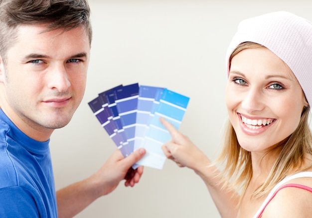 Pareja alegre con muestras de color para pintar una habitación