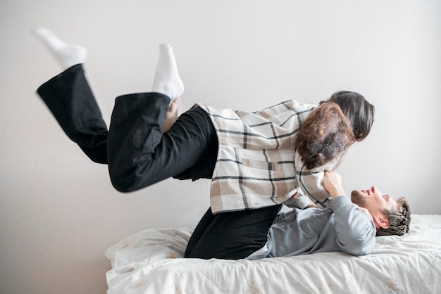 Una pareja alegre participa en una actividad alegre y lúdica en una cama acogedora compartiendo un momento de diversión