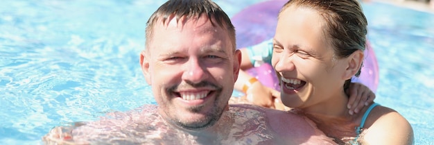 Pareja alegre posando para una foto en la piscina en un resort de lujo