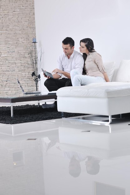 una pareja alegre se relaja y trabaja en una computadora portátil en la moderna sala de estar interior de la casa