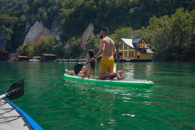 Pareja alegre en el stand up paddle board