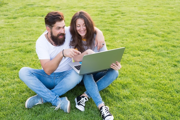 Pareja alegre viendo la serie portátil al aire libre concepto de aire fresco