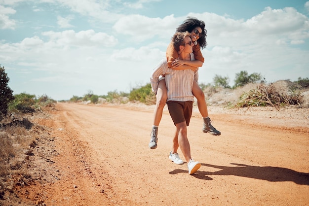 Pareja ama y viaja con un hombre y una mujer caminando juntos por un camino de arena en el desierto o en la naturaleza Romance de verano y citas con un joven feliz que lleva a cuestas a una mujer en la naturaleza