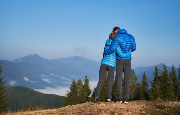 Pareja amante de los turistas caminando en las montañas en un día soleado