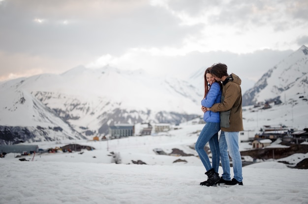 Pareja de amantes, abrazándose en la escena de montañas nevadas y riendo