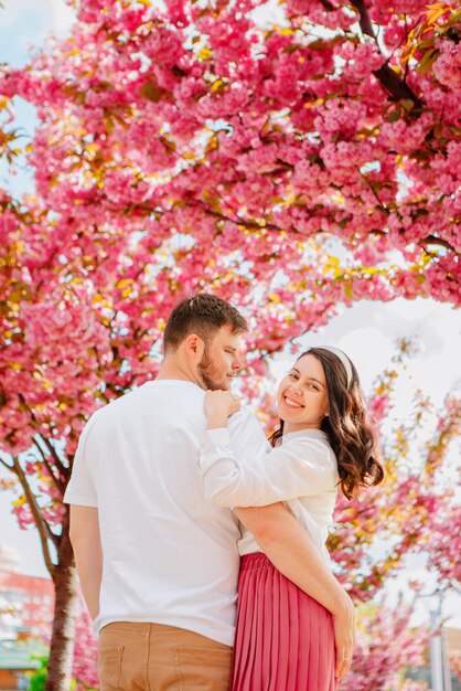 Foto una pareja de amantes bajo un árbol de sakura en flor.