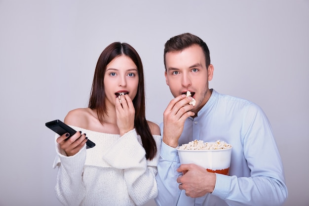 Pareja de amantes comiendo palomitas de caramelo o saladas con presagios mientras ven películas en el cine en casa