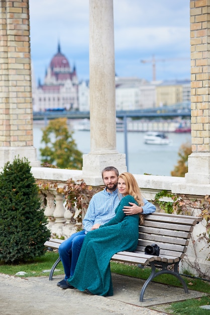 Pareja de amantes se sienta en un banco cerca de las columnas sobre un fondo borroso de la arquitectura de Budapest