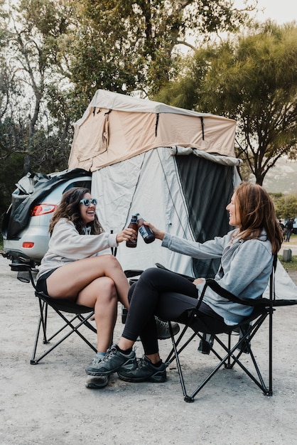 Una pareja de amigas felices disfrutan de cervezas en un campamento