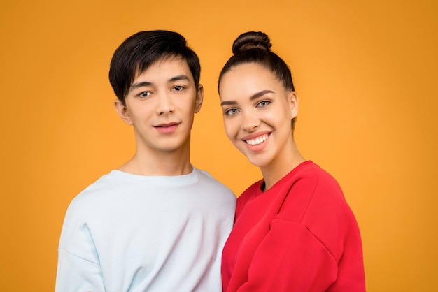 pareja de amor sonriendo y tomando una foto de retrato de fondo naranja