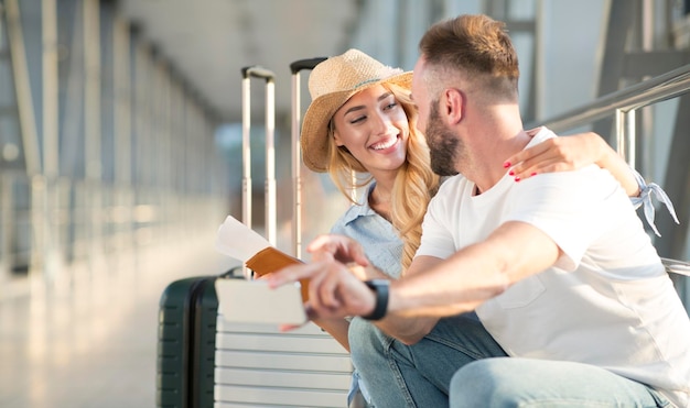 Pareja amorosa en el aeropuerto usando la aplicación de viaje en el teléfono inteligente