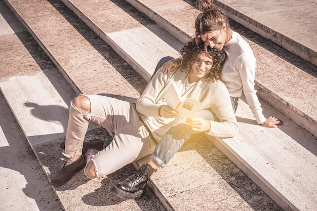 Pareja amorosa al aire libre se acuesta en una escapada a la ciudad leyendo un libro juntos