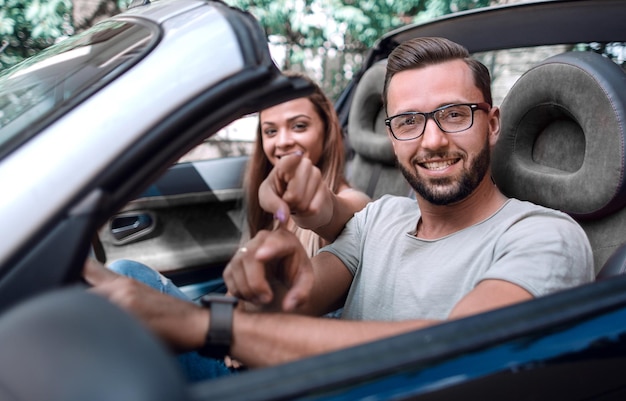 Pareja amorosa en un auto convertible apuntándote