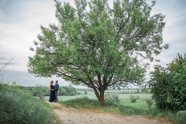 Una pareja amorosa camina en el campo, la niña está embarazada. Camine al aire libre. Amor y cuidado.