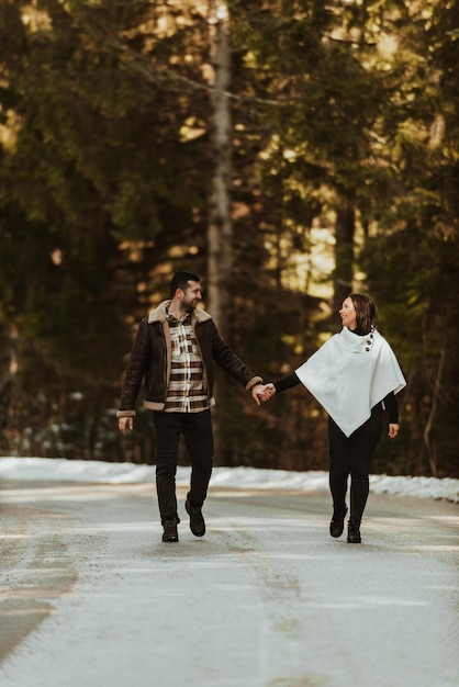 Pareja amorosa caminando a través de una carretera congelada nevada en la naturaleza invernal y tomándose de la mano Enfoque selectivo