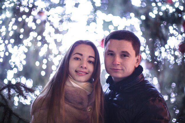 Pareja amorosa cerca del árbol de Navidad en la noche al aire libre