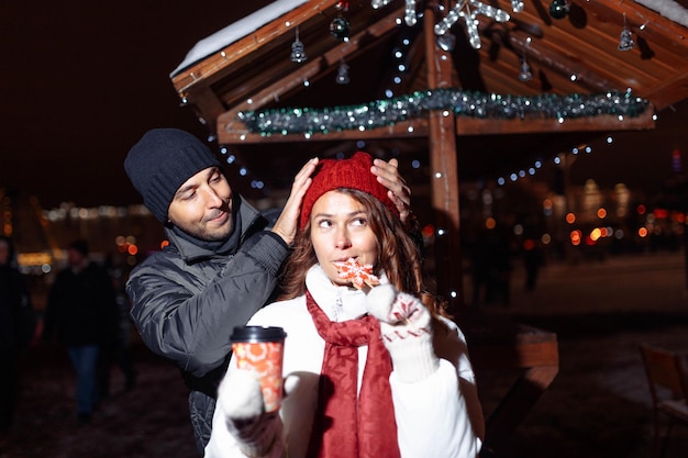 Una pareja amorosa en la ciudad camina bebiendo café con dulces navideños en invierno.