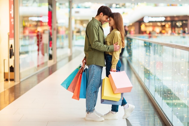 Pareja amorosa comprando juntos abrazando de pie en el hipermercado moderno